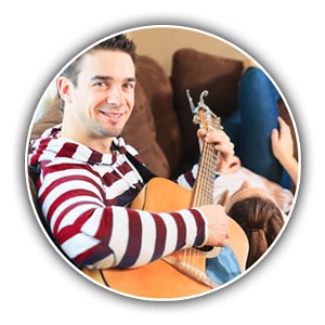 Mann und Frau mit Gitarra auf Sofa